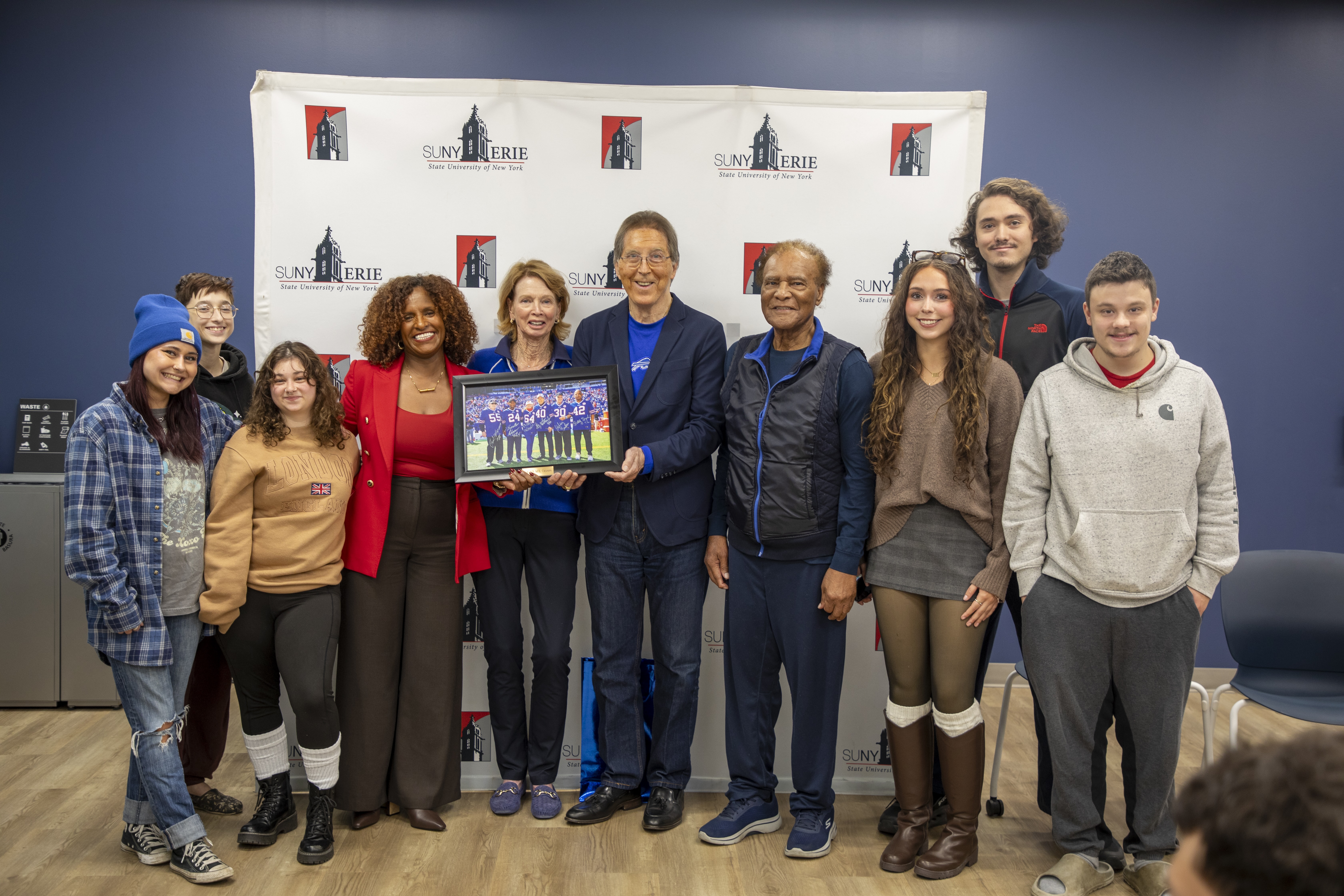 SUNY Erie President Dr. Adiam Tsegai recieving photo from Ed Rutkowski with a crowd of students.