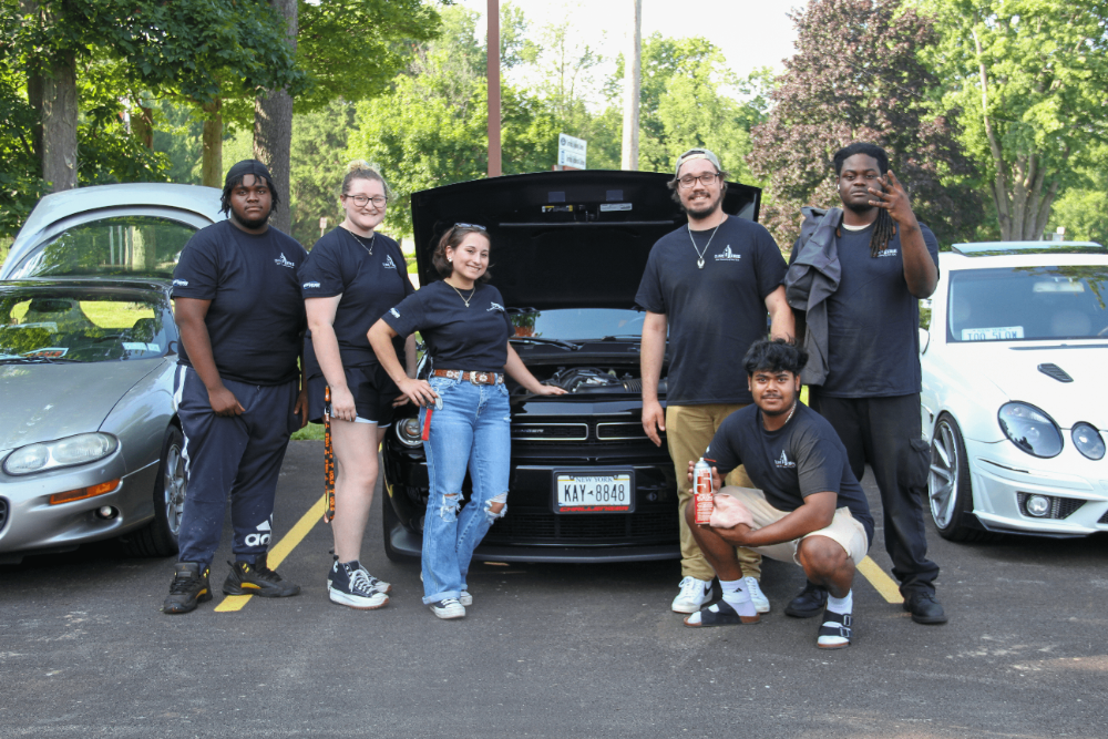 6 Students standing infront of a Dodge Challenger they worked on in classes.