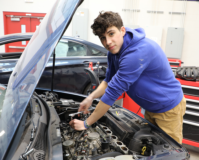 Student participating in a work-study working on an automobile